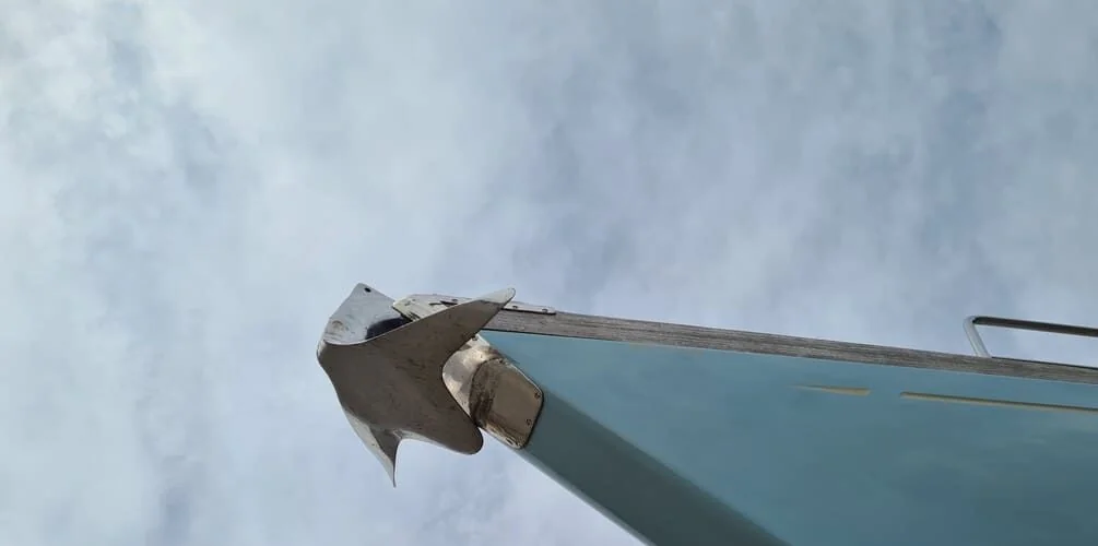 Boat bow cleat and weathered hull detail against overcast sky, showing marine wear.