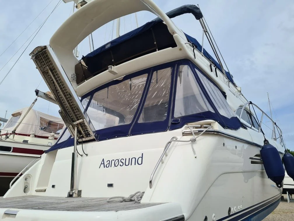Multi-deck recreational powerboat moored at marina with canvas canopy and cabin windows visible.