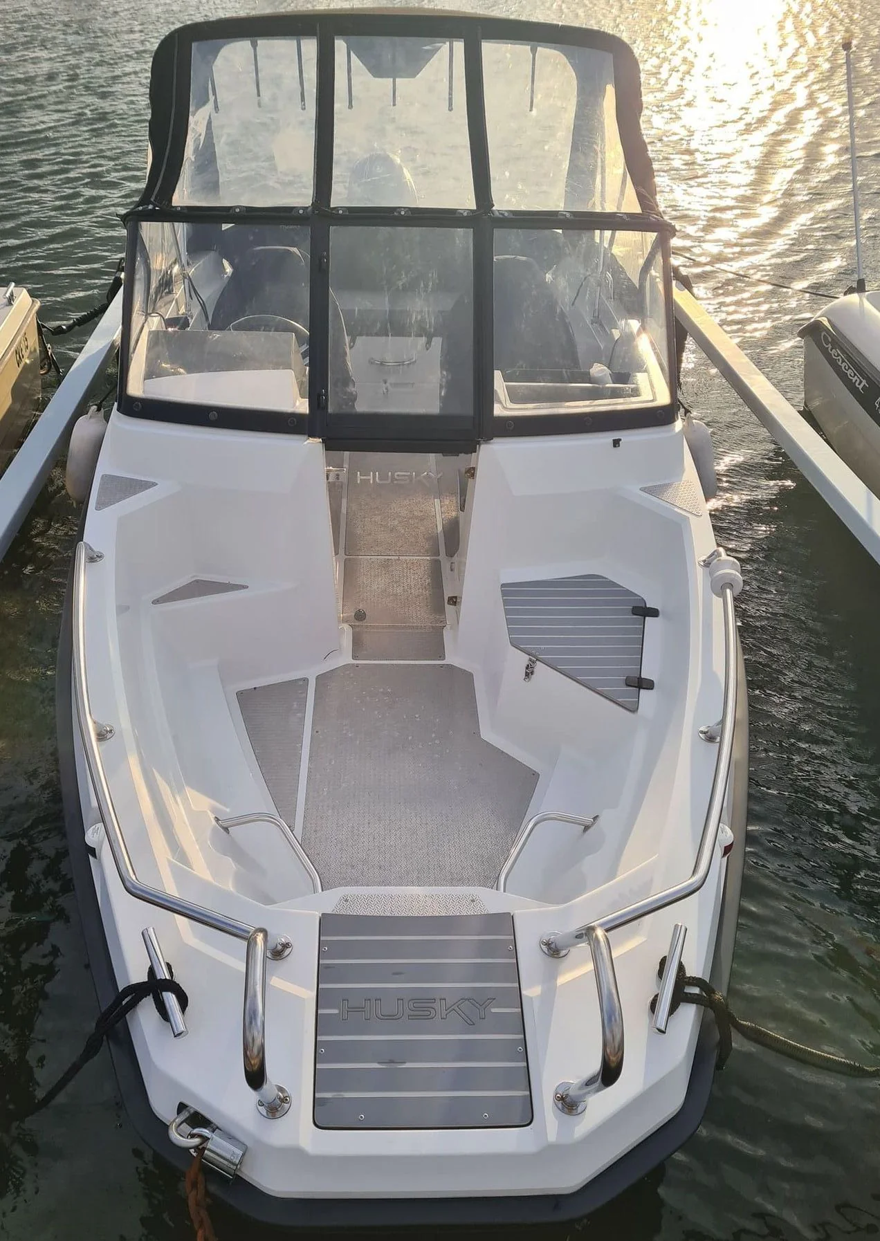 Overhead view of white recreational powerboat moored in calm water with canvas canopy and windshield.