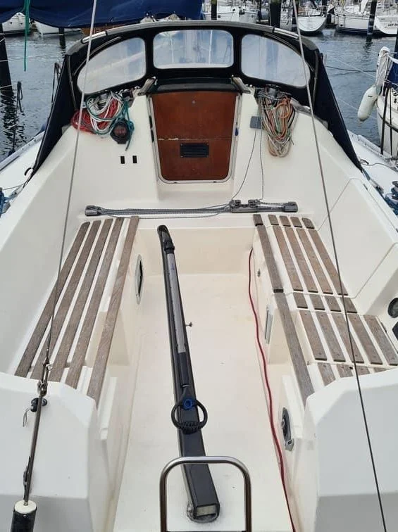 Overhead view of recreational powerboat deck with coiled rope, electrical cables, and marine equipment at dock.