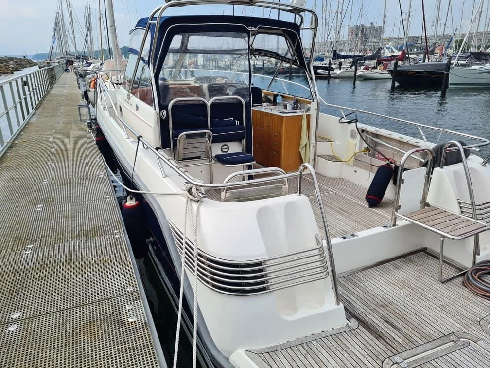 Recreational powerboat moored at marina dock with open cabin and seating visible.