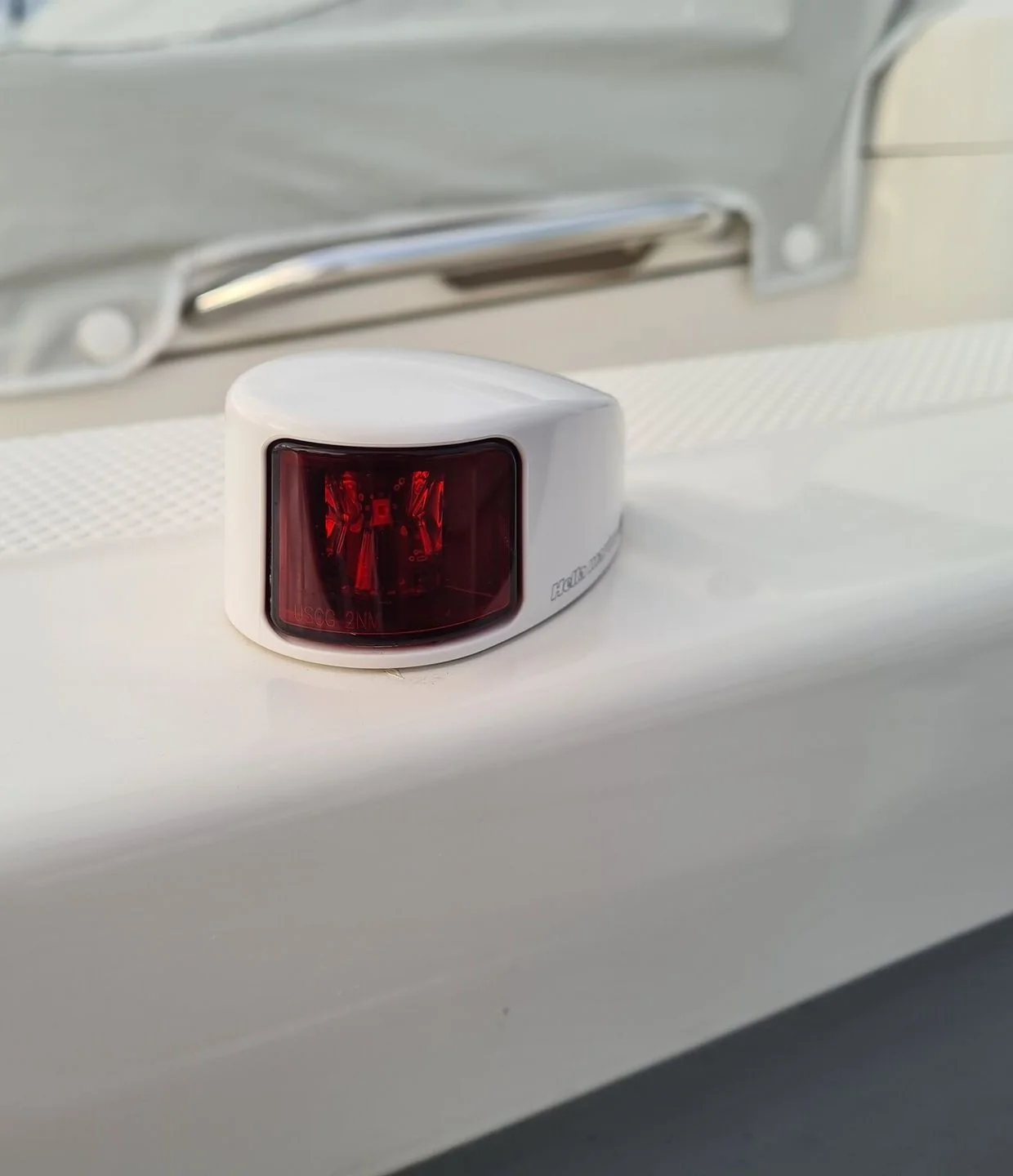 Navigation light with red lens mounted on white boat cabin exterior.