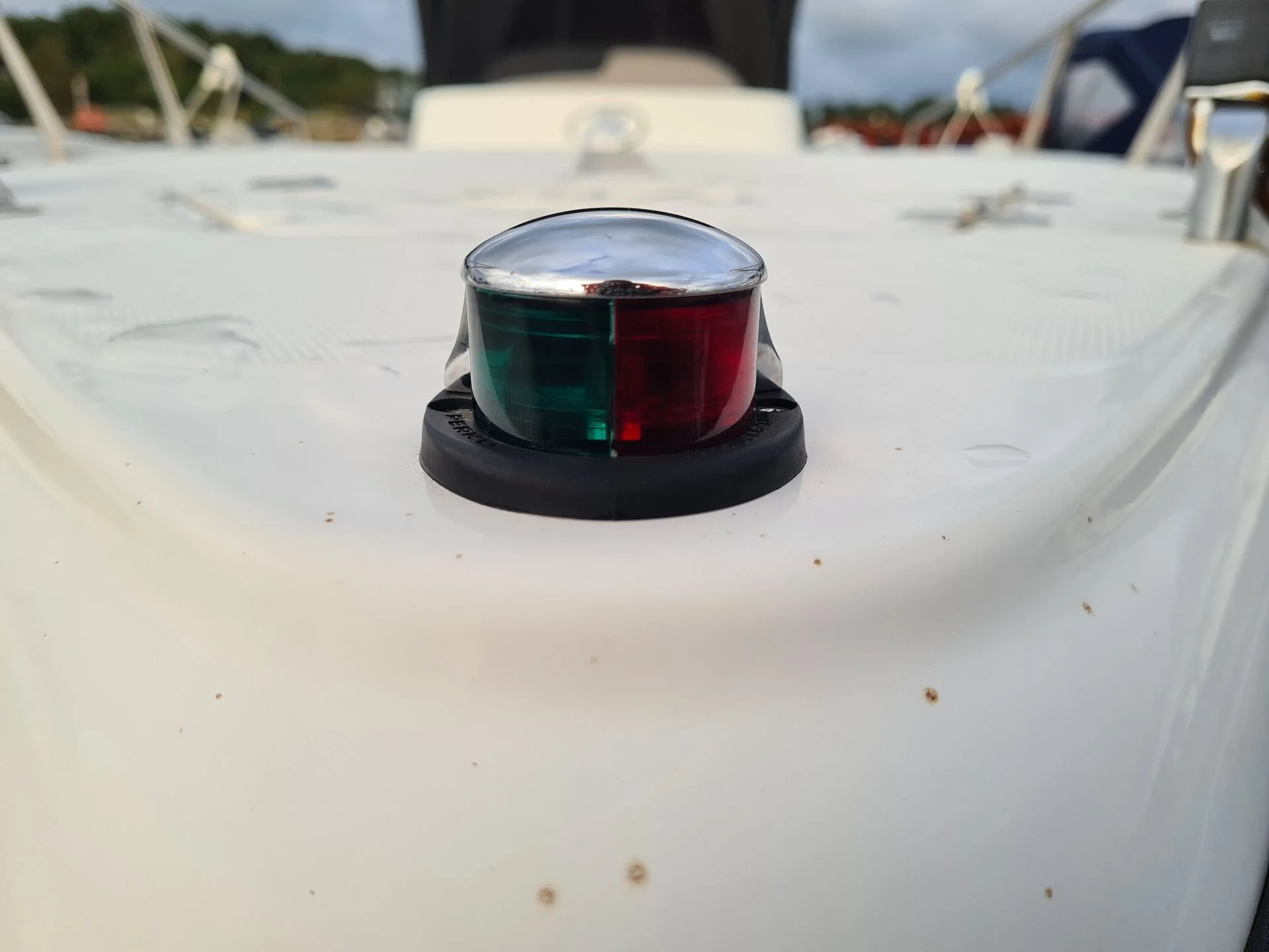 Navigation light mounted on boat cabin roof with green and red lens covers.