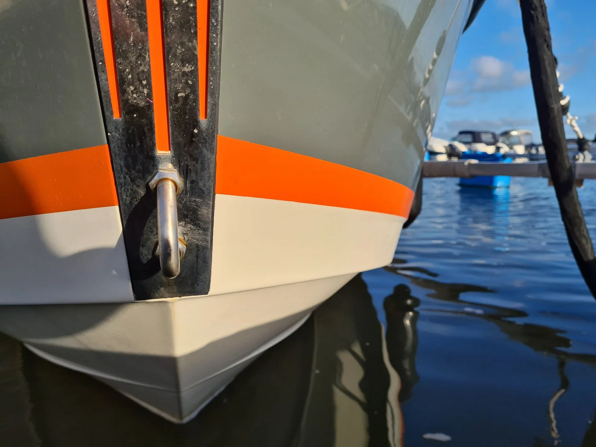Close-up of boat transom hardware and cleat with orange and white hull stripe, dockside in Cape Coral.