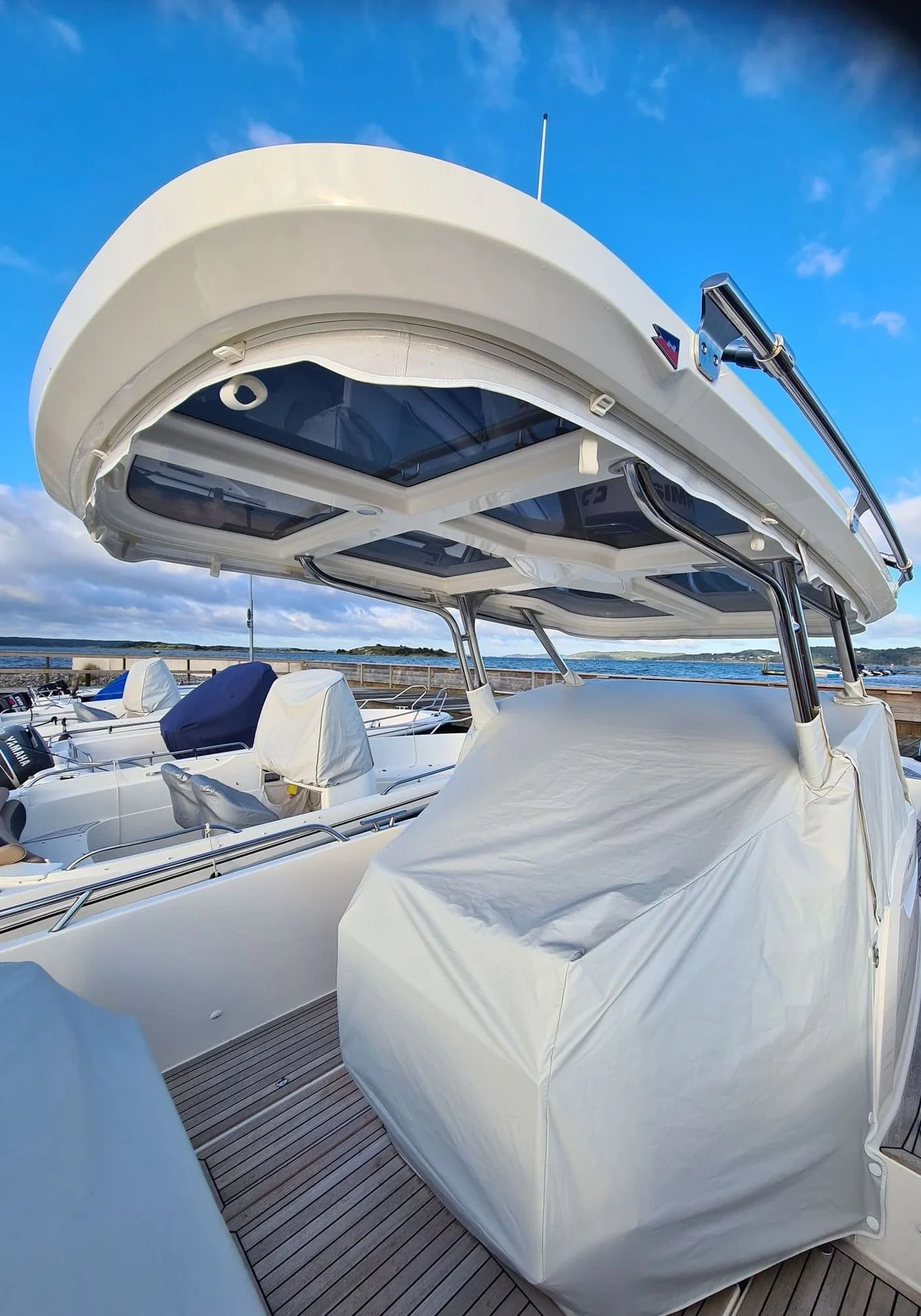 Boat canvas canopy extended over deck with protective covering on sunny day.