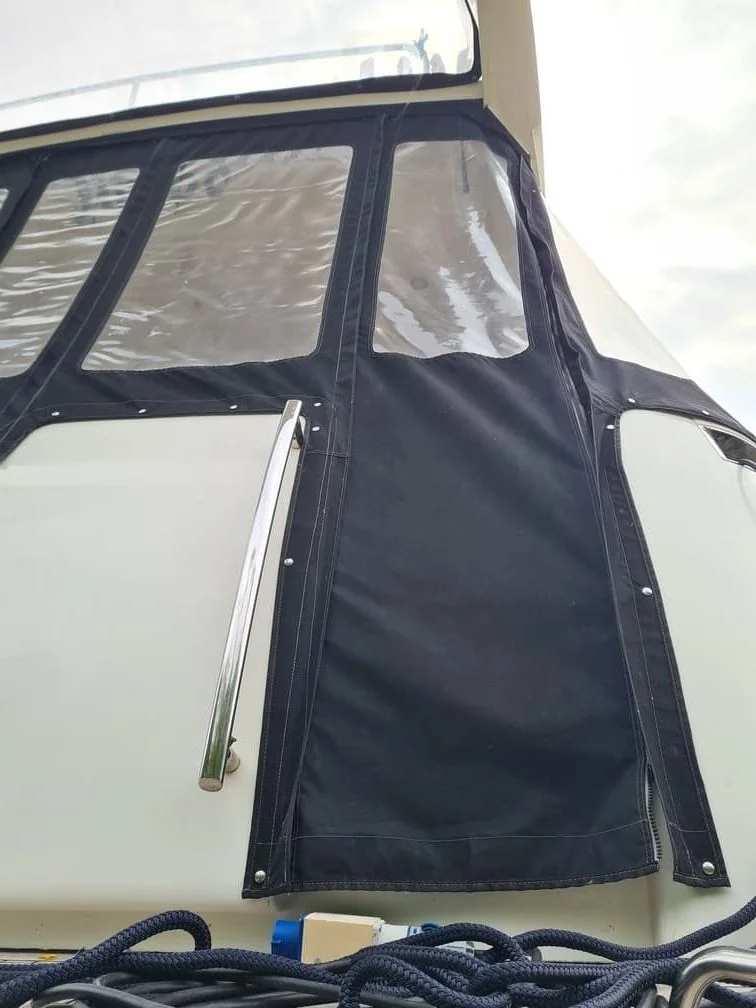 Boat canvas enclosure with clear windows and black fabric panels, mooring rope visible below.