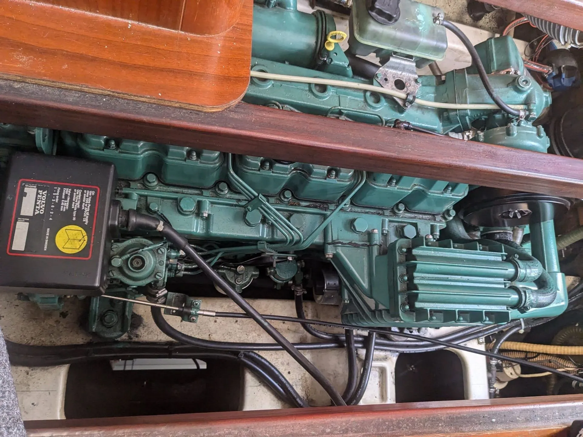 Inboard marine engine with green cylinder heads and control panel visible inside boat hull.