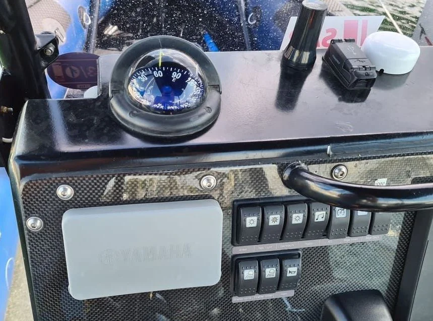 Marine compass and control panel with switches mounted on boat dashboard.
