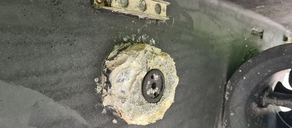 Corroded outboard motor mounting bracket with heavy salt and mineral buildup on marine engine block.