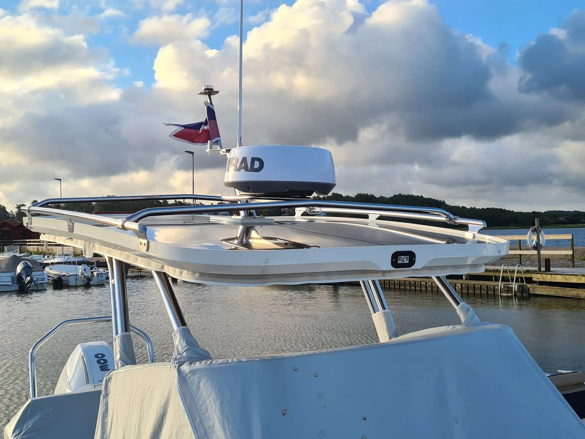 Recreational powerboat moored at marina dock with radar equipment and outboard motor visible.