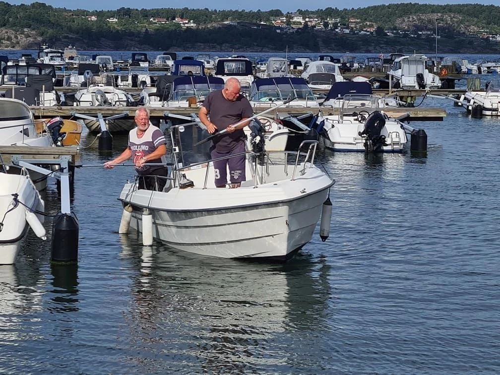 Two men inspect outboard motor on recreational boat in Cape Coral marina.