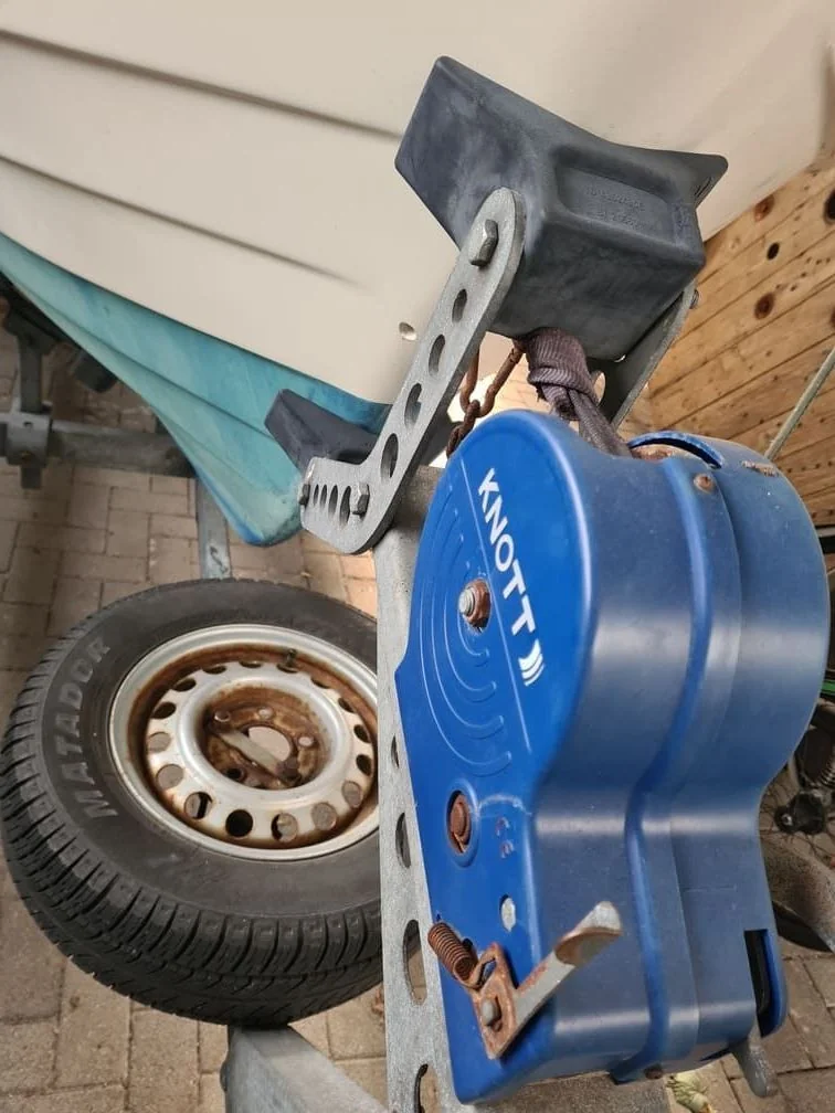 Boat trailer winch and wheel assembly undergoing inspection during maintenance service.