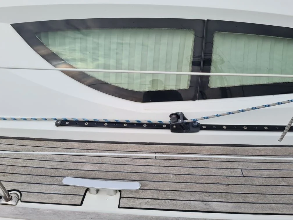 Boat windshield with tinted glass panels mounted on white hull above weathered wooden dock.