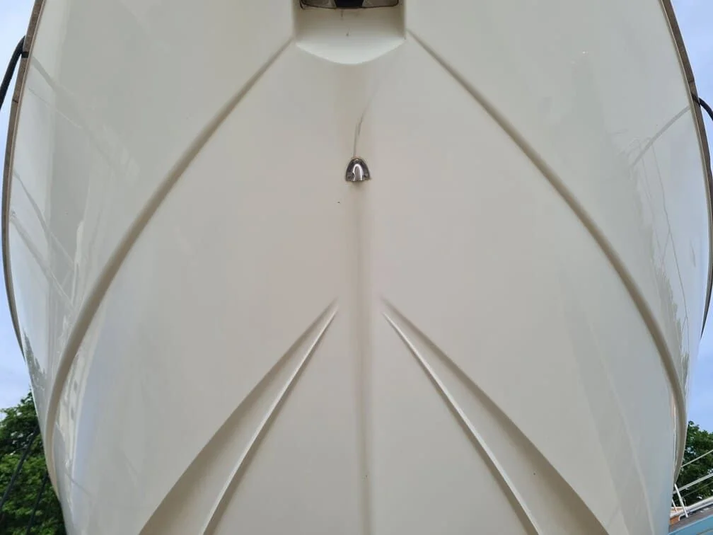 Boat hull interior viewed from bow, showing white fiberglass cabin structure and anchor line.