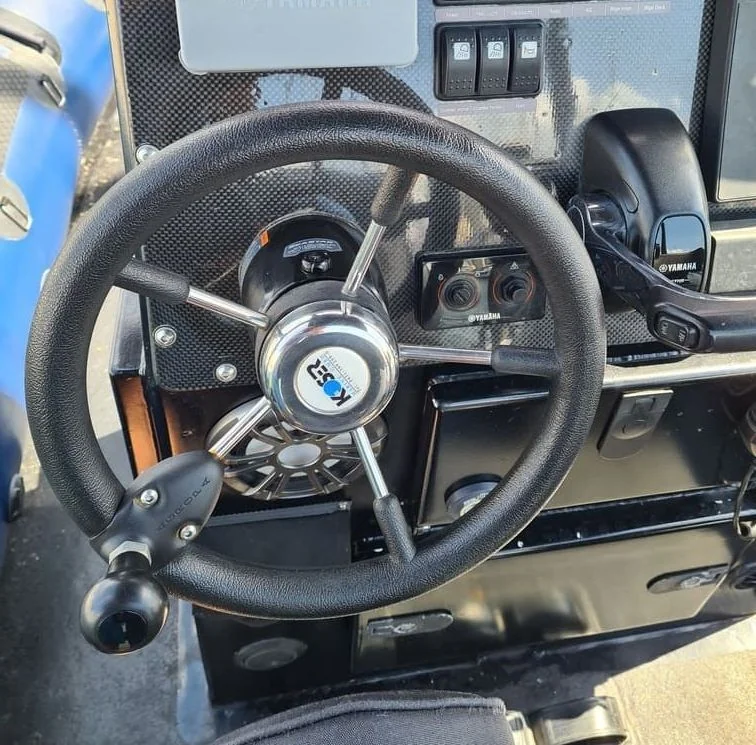 Boat steering wheel and control panel with Yamaha outboard motor controls in bright daylight.