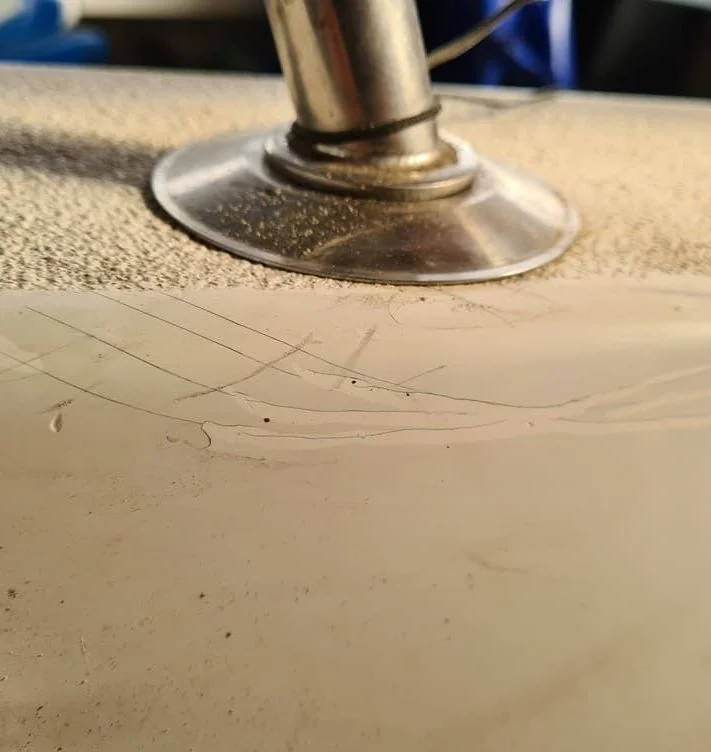 Close-up of boat canvas repair work showing stitching detail and metal fastener on fabric surface.