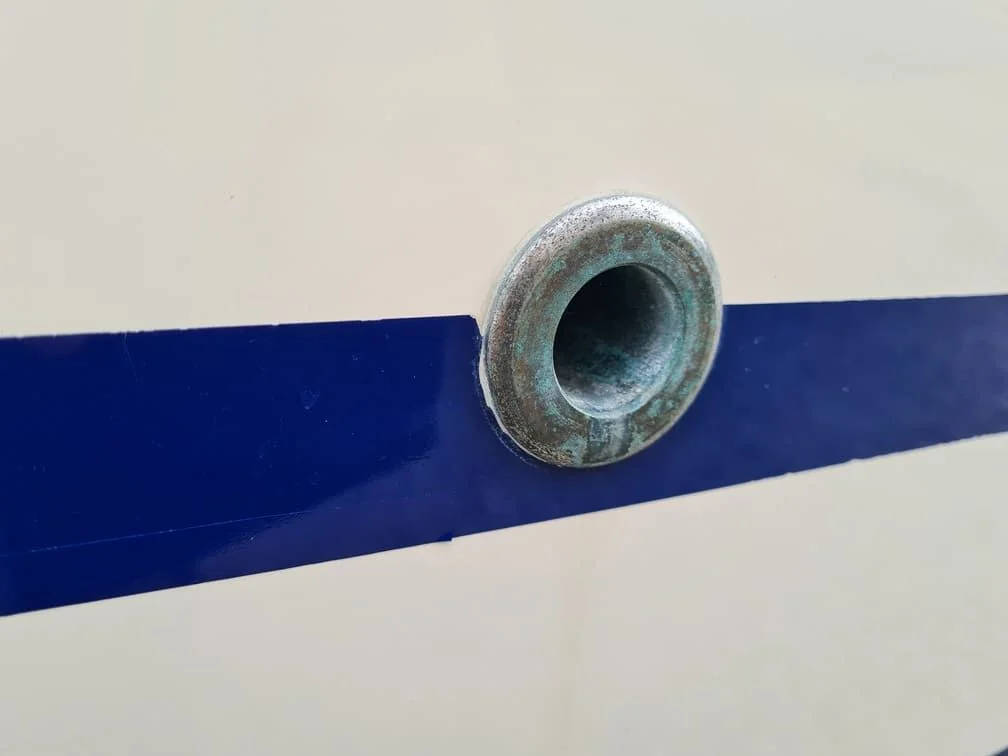Corroded through-hull fitting on boat hull showing marine growth and oxidation damage.