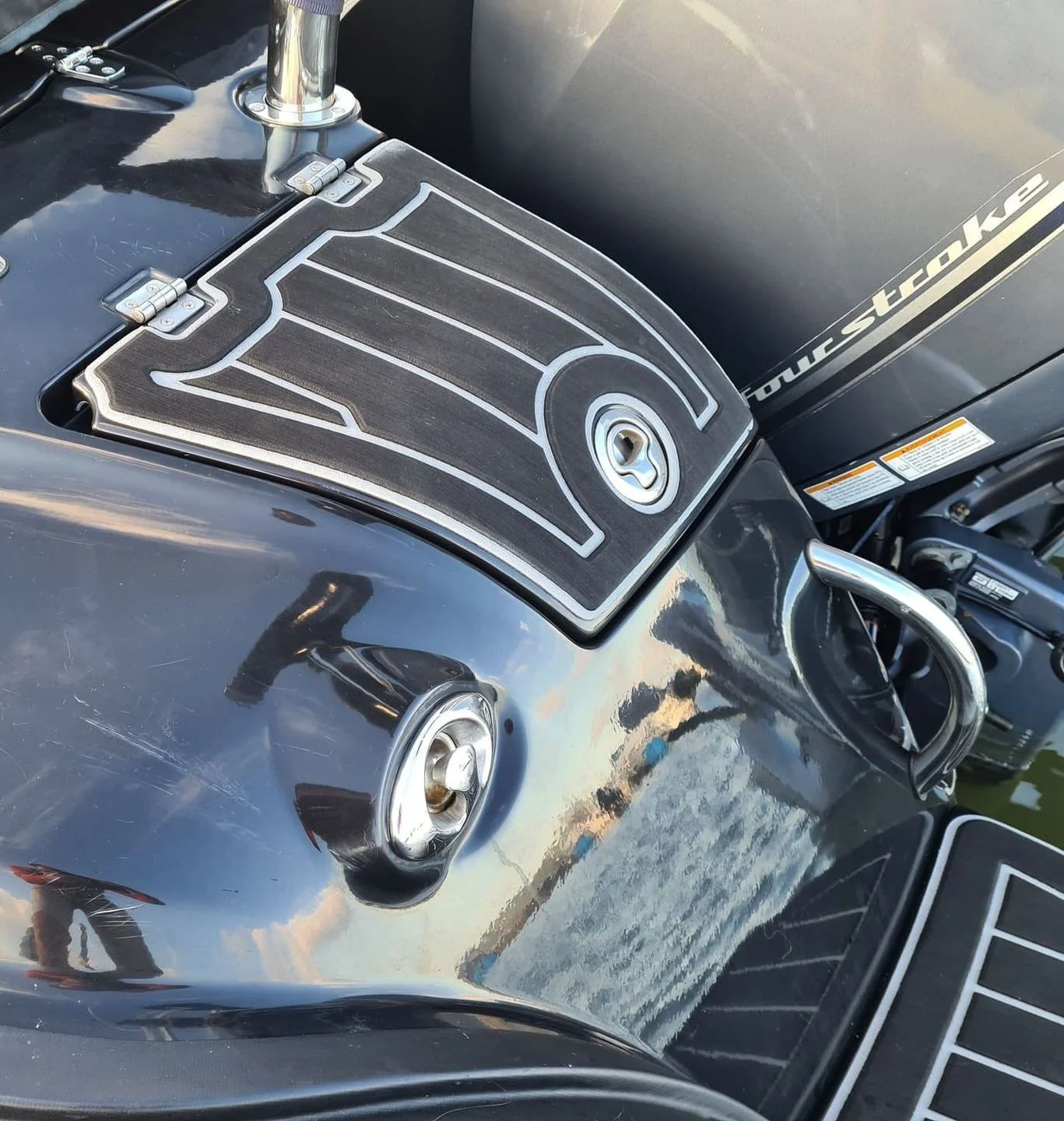 Outboard motor engine cover with stylized graphics displayed on boat hull in sunlight.